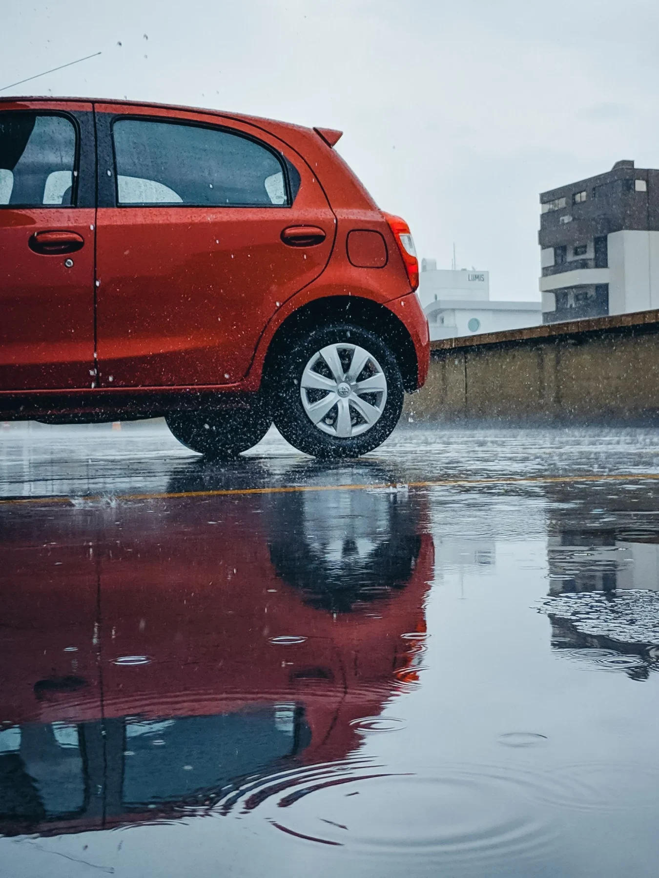 Auto rojo estacionado sobre un suelo mojado